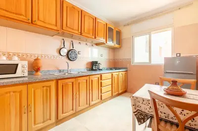 a kitchen with wooden cabinets and a sink and a table at Appartement spacieux Centre Marrakech in Marrakech