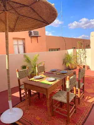 a wooden table with chairs and an umbrella on a patio at Riad Safran Rouge Jacuzzi RoofTop in Marrakech