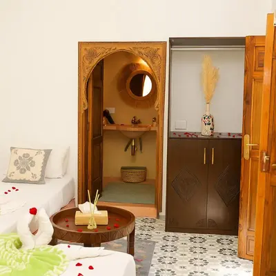 a bedroom with a bed and a table and a door at Riad Safran Rouge Jacuzzi RoofTop in Marrakech