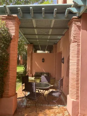 a patio with a table and chairs under a pergola at Palmeraie Village 2 - Cosi appartement en Rez de Jardin in Marrakech