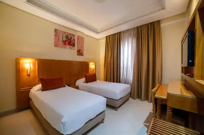 a hotel room with two beds and a desk at Hotel Palais Al Bahja in Marrakech