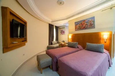 a hotel room with two beds and a tv at Hotel Palais Al Bahja in Marrakech