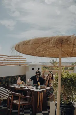a man and woman sitting at a table under an umbrella at Le Petit Kenzara & magical rooftop in Marrakech