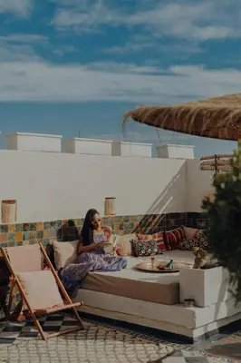 a woman sitting on a couch on a patio at Le Petit Kenzara & magical rooftop in Marrakech