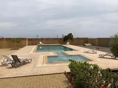 a swimming pool with two chairs and a fence at Villa 5 chambres route de Casablanca Marrakech in Marrakech