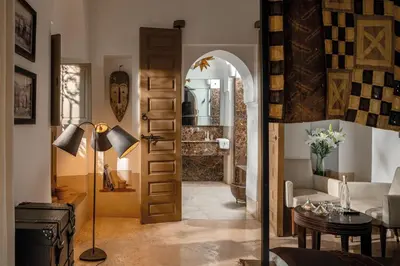 a living room with a door leading into a room with a table at Riad Jaaneman in Marrakech