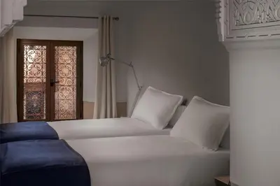 a white bed with white pillows and a window at Riad Jaaneman in Marrakech