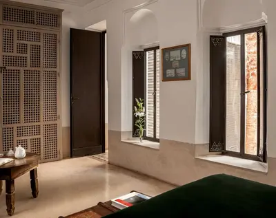 a living room with windows and a table and a couch at Riad Jaaneman in Marrakech