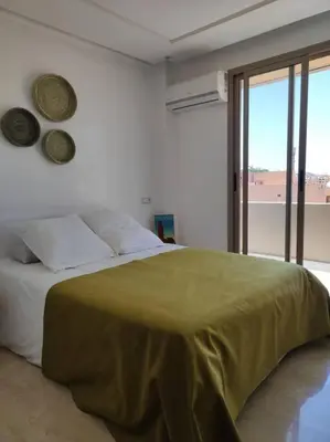 a bedroom with a bed with a green blanket on it at Plein centre Marrakech, grand balcon filant in Marrakech