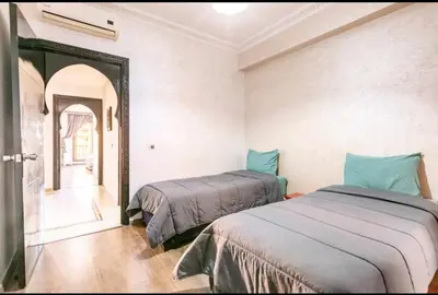 a bedroom with two beds and a mirror in it at Superbe appartement en plein centre à Gueliz in Marrakech