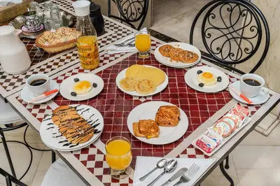 a table topped with plates of breakfast food and orange juice at Riad Mandana & Spa in Marrakech