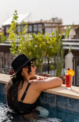 a woman in a hat sitting in a swimming pool at Riad Mandana & Spa in Marrakech