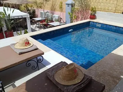 a swimming pool with two hats on a table next to it at Riad Mandana & Spa in Marrakech