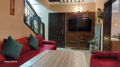 a living room with a red couch and a flat screen tv at Riad Habib - Traditional Moroccan 3 bedroom family home in Marrakech