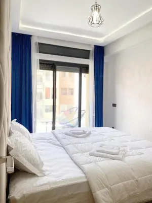 a bedroom with a large bed with blue curtains and a window at Modern 3-Bedroom apartment with Balcony-Central Gueliz Marrakech in Marrakech