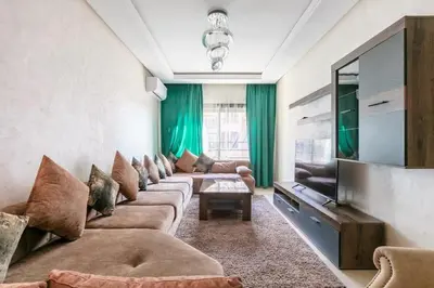 a living room with a long couch and a television at Modern 3-Bedroom apartment with Balcony-Central Gueliz Marrakech in Marrakech