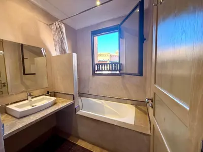 a bathroom with a sink and a tub and a window at Beach Mama Waky Marrakech Appartement Premium Piscine & Vue Atlas in Marrakech