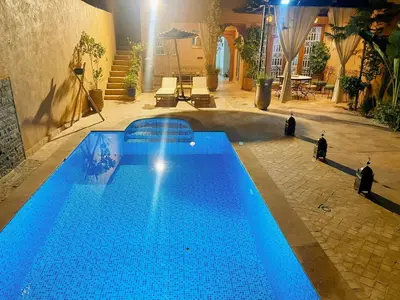 a large blue swimming pool with people standing around it at Villa brek in Marrakech