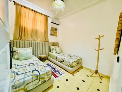 a bedroom with two beds and a cross on the wall at Villa brek in Marrakech