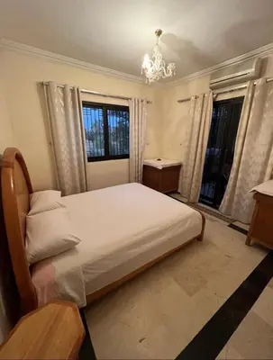 a bedroom with a large bed and two windows at Superbe appartement équipé en résidence propre avec Piscine in Marrakech