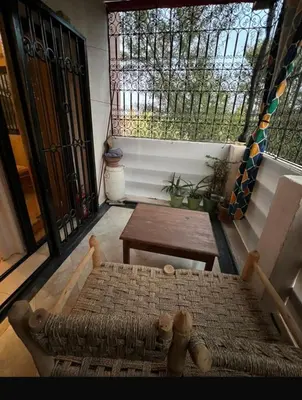 a porch with a bench and a table and a window at Superbe appartement équipé en résidence propre avec Piscine in Marrakech
