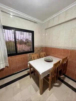 a dining room with a table and chairs and a window at Superbe appartement équipé en résidence propre avec Piscine in Marrakech