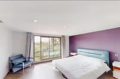 a bedroom with a bed and a chair and a window at Duplex Moderne 233m2 dans une magnifique résidence in Marrakech