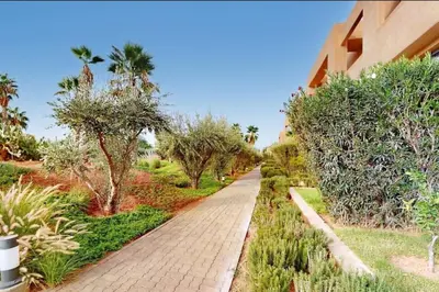 a brick walkway in a garden with trees and bushes at Duplex Moderne 233m2 dans une magnifique résidence in Marrakech