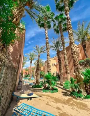 a beach with palm trees and lounge chairs and a surfboard at Riad QAYS in Marrakech