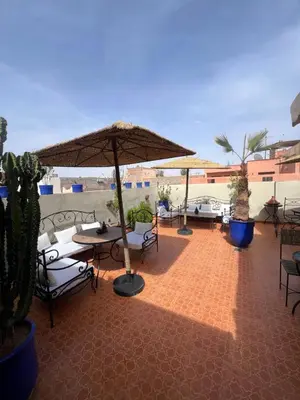 a patio with tables and chairs and umbrellas at Riad La Perla Bianca in Marrakech