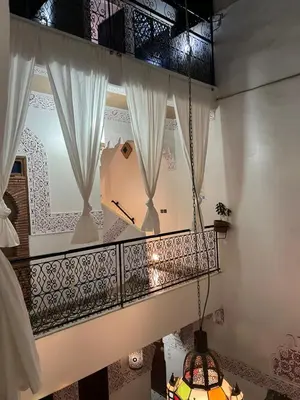 a room with a balcony with white curtains at Riad La Perla Bianca in Marrakech