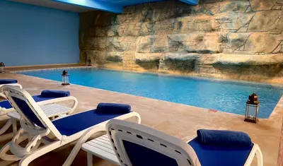 a swimming pool with chairs and a rock wall at El Olivar Palace Marrakech All Inclusive, Aquapark & SPA in Marrakech