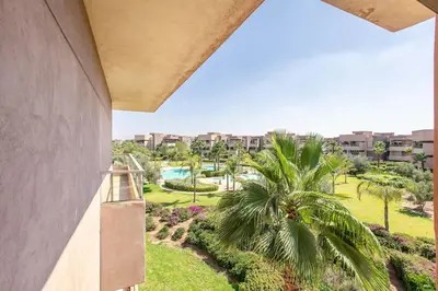 a balcony view of a resort with a palm tree at Résidence golfique, jardin, piscine in Marrakech