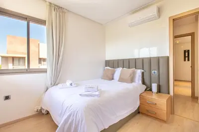 a bedroom with a large white bed and a window at Résidence golfique, jardin, piscine in Marrakech