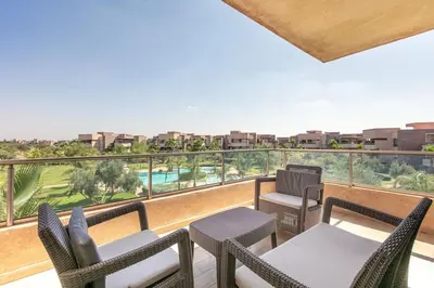 a balcony with chairs and tables and a view of a pool at Résidence golfique, jardin, piscine in Marrakech