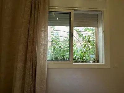 a window with a curtain in a room with a plant at Appartement propre au centre de Marrakech in Marrakech