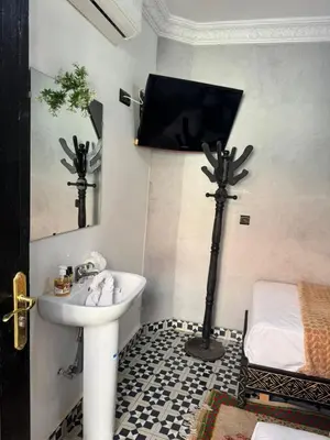 a bathroom with a sink and a tv on the wall at Riad Douja in Marrakech