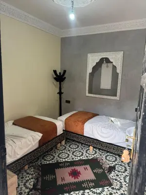 a bedroom with two beds and a rug at Riad Douja in Marrakech