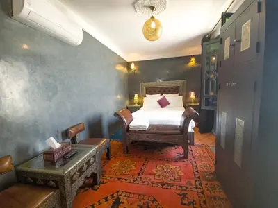 a bedroom with a bed and a chair in a room at Riad Jaime in Marrakech