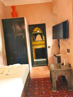 a room with a bed and a tv and a table at Riad Jaime in Marrakech