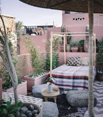 a patio with a bed and lots of potted plants at Riad Nadara, superbe riad au coeur de la medina! in Marrakech