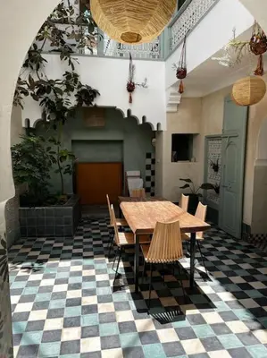 a room with a table and chairs on a checkered floor at Riad Nadara, superbe riad au coeur de la medina! in Marrakech