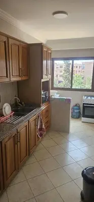a kitchen with wooden cabinets and a tile floor at Superbe appartement à Marrakech quartier Majorelle 2 chambres in Marrakech