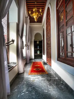 a hallway with a red rug and a chandelier at Palais Aix Kabaj &Spa in Marrakech