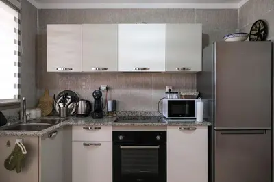 a kitchen with white cabinets and a refrigerator at Magnifique appart vue piscine in Marrakech