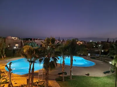 a large blue swimming pool with palm trees in a city at La Perle de Marrakech by Atlas Golf Resort in Marrakech