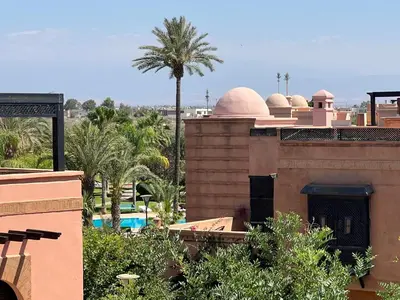 a view of a building with a palm tree and a pool at La Perle de Marrakech by Atlas Golf Resort in Marrakech