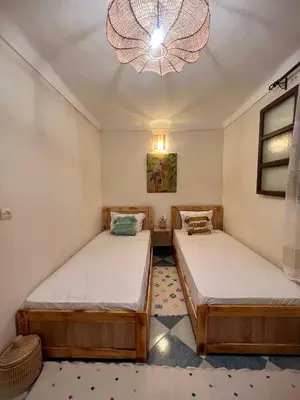 two beds in a room with a chandelier at Peekaboo Hostel in Marrakech