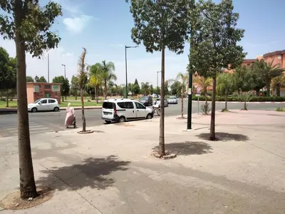 a street with cars parked in a parking lot with trees at les porte de guiliz appartement in Marrakech