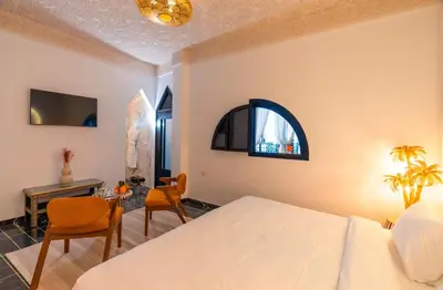 a bedroom with a bed and a table and chairs at Riad L'ECOLE in Marrakech